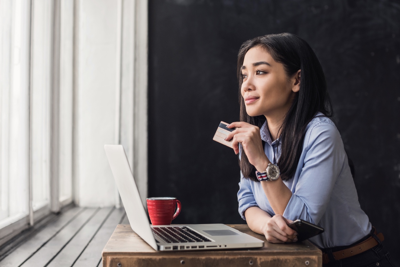 Woman at laptop with flex spending card in hand