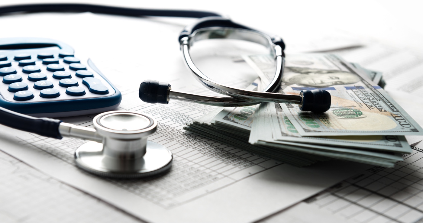 Medical bill, calculator, stethoscope, and money on a desk